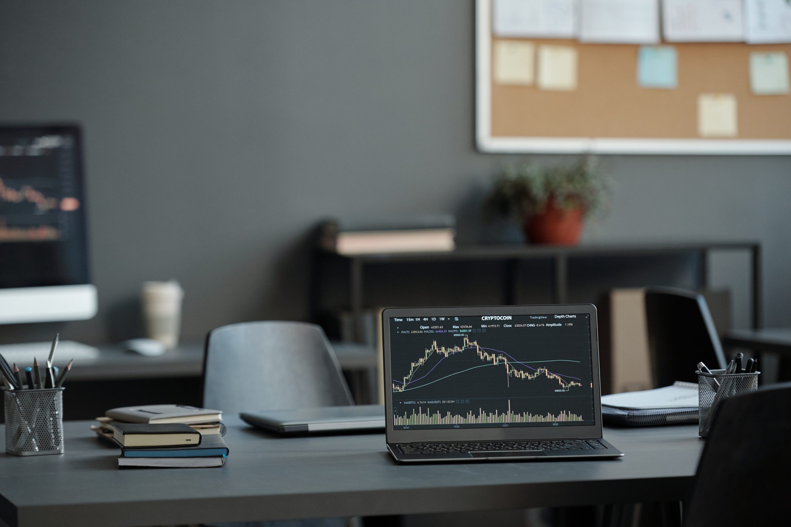 Laptop with graphic financial data on screen standing on desk which is workplace of analyst creating illustrations of market development